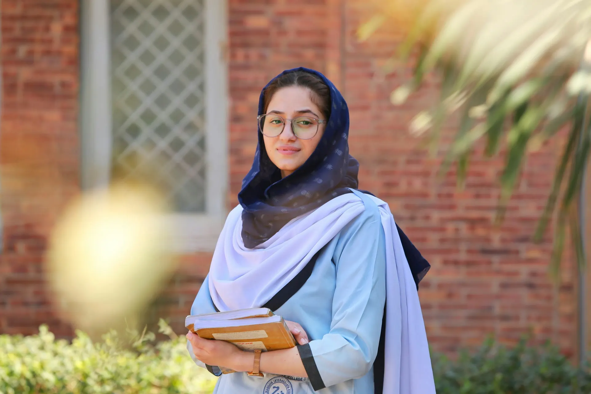 College student holding her books outside a campus building